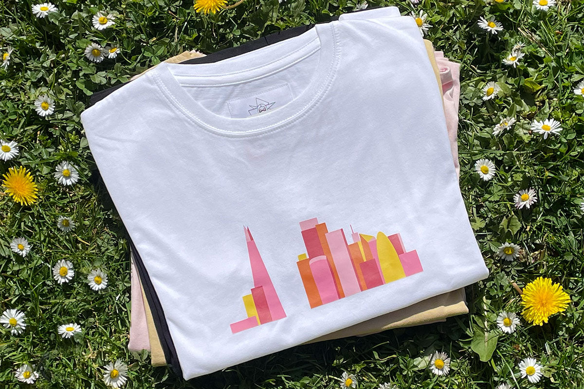 A pile of folded tees with a t-shirt with pink print on top.