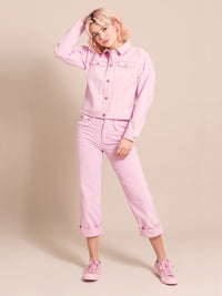 Woman wearing a light pink denim set - a jacket with front pockets and frayed elements  and mom's jeans
