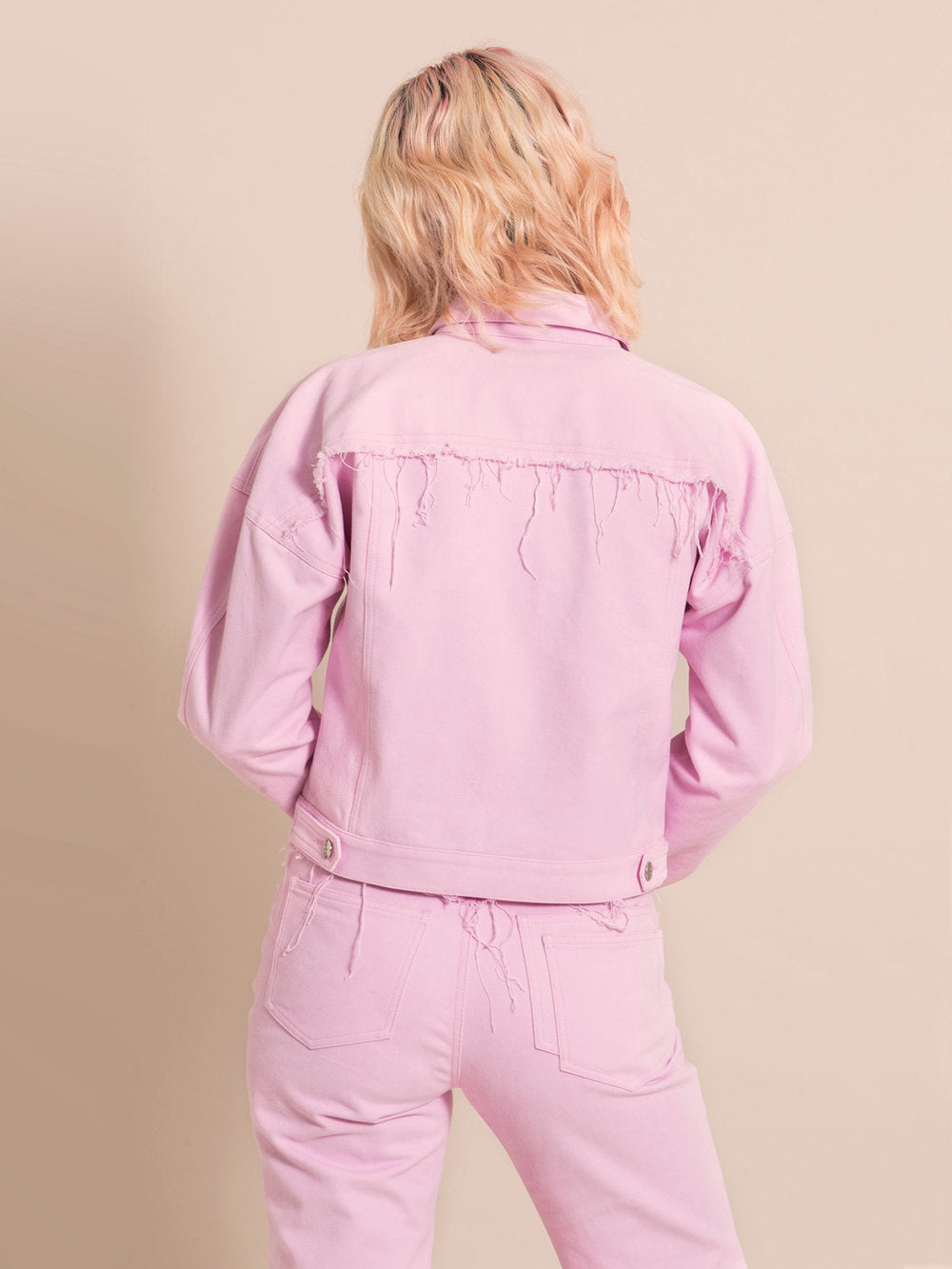 Backshot of a light pink upcycled jacket with frayed elements