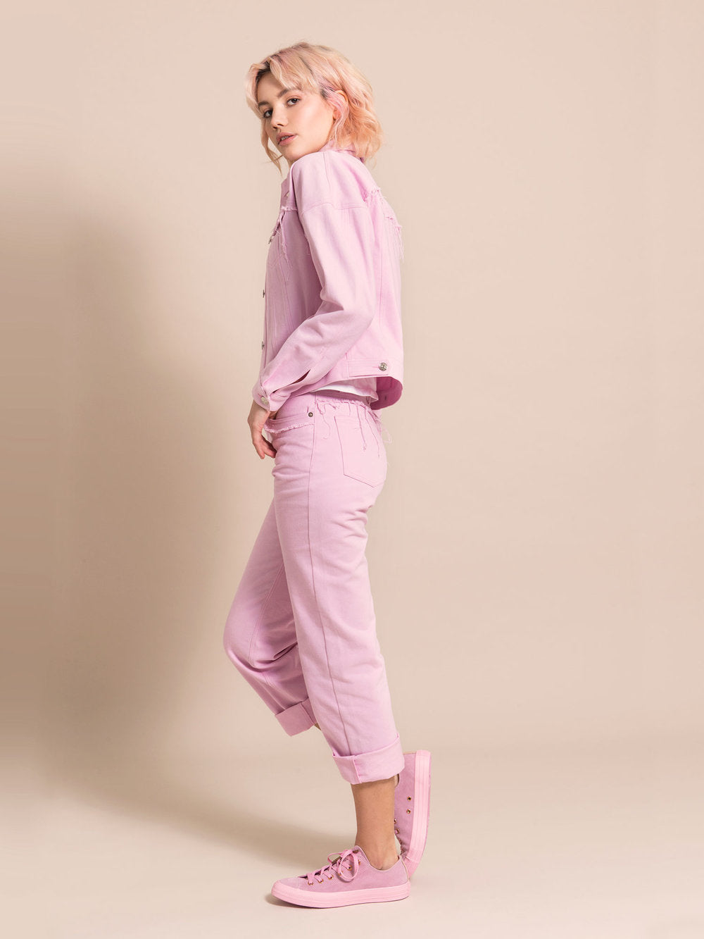 Sideshot of a woman wearing a pink denim set - jacket and rolled-up mom's jeans