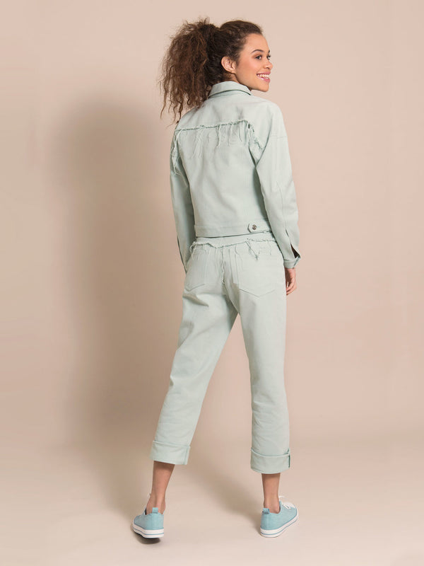 Backshot of a happy girl wearing a denim jacket and jeans in light blue with flared details