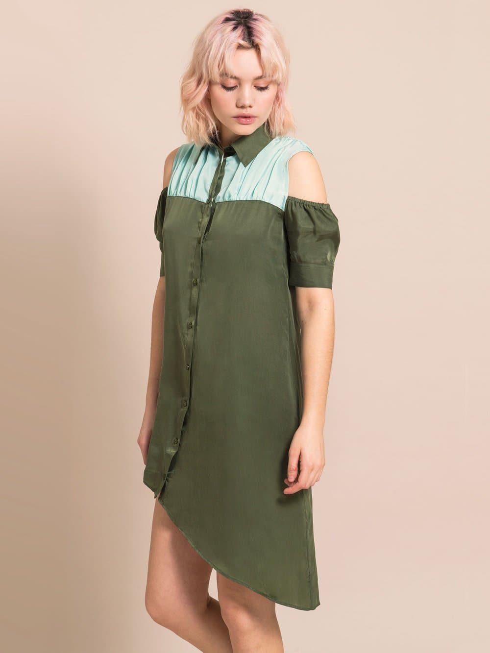 Blond woman wearing a sustainable, cold-shoulder, above-the-knee, assymtric dress in military green with light blue details around the shoulders