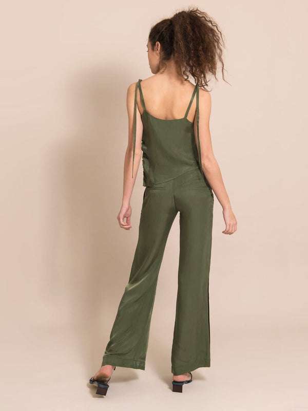 Backshot of a woman wearing a sustainable set in military green - a sleeveless top with adjustable shoulder straps and loose, flared, summer  trousers
