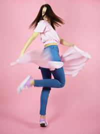 a creative shot of blonde gone rogue's summer outfit in pink - the set of wildflower surplice crop top and the skinny sustainable jeans.