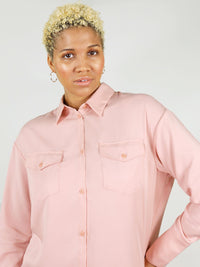 Buttoned up close-up shot of the summer shirt in blushing pink. Relaxed shoulders and lose collar for extra comfort. Large front pockets and buttons down the wrist.