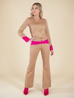 Woman wearing a sustainable beige blouse and flared trousers with neon pink elemenets