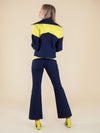 Backshot of a woman wearing upcycled navy blue bomber jacket and flared trousers with yellow elemements