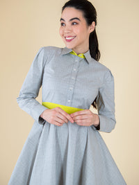 Woman wearing a grey upcycled dress with long sleeves and yellow elements