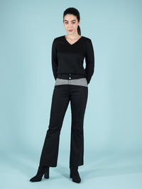 Frontshot of a woman wearing a black sustainable blouse and flared troursers with checker elements