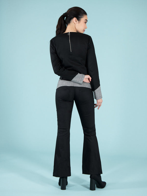 Backshot of a woman wearing a sustainable black blouse and flared trousers with checker details