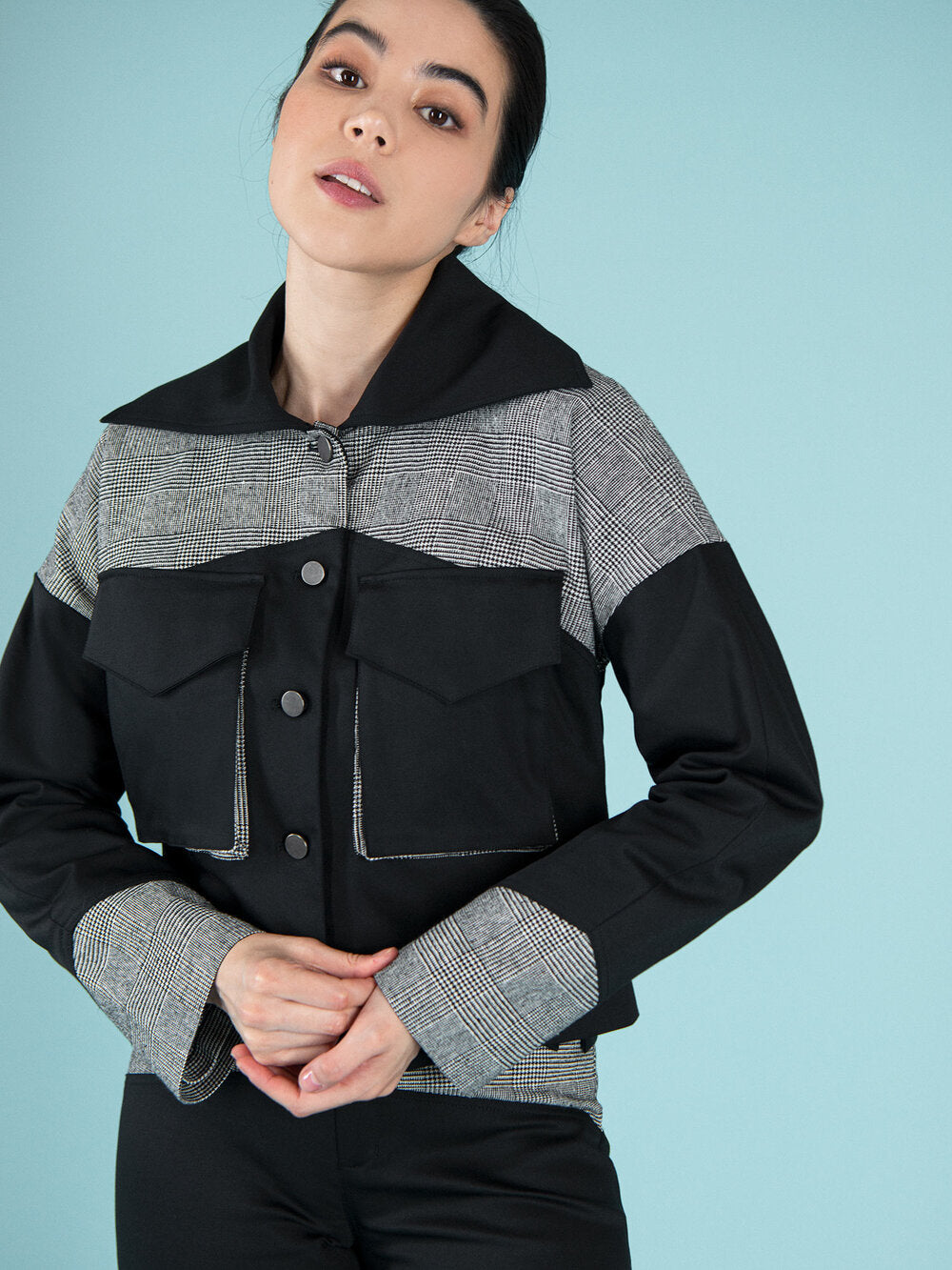Close shot of a woman wearing a black bomber jacket with checker elements
