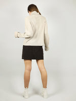 The back view of the turtleneck in beige shows that it has loose fit and extra long sleeves for added comfort. Long roll neck pullover and hips length for extra warmth.