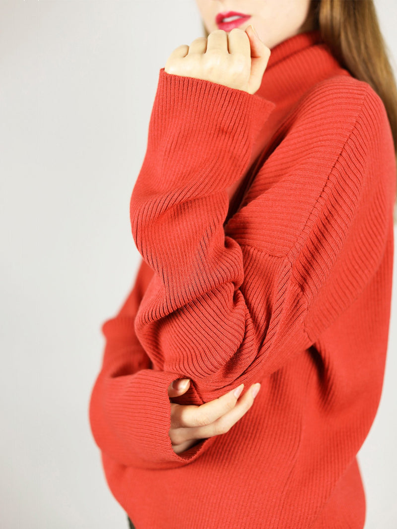 The organic cotton turtleneck has extra long sleeves and comes in bright red. It has comfortable, slightly loose fit.