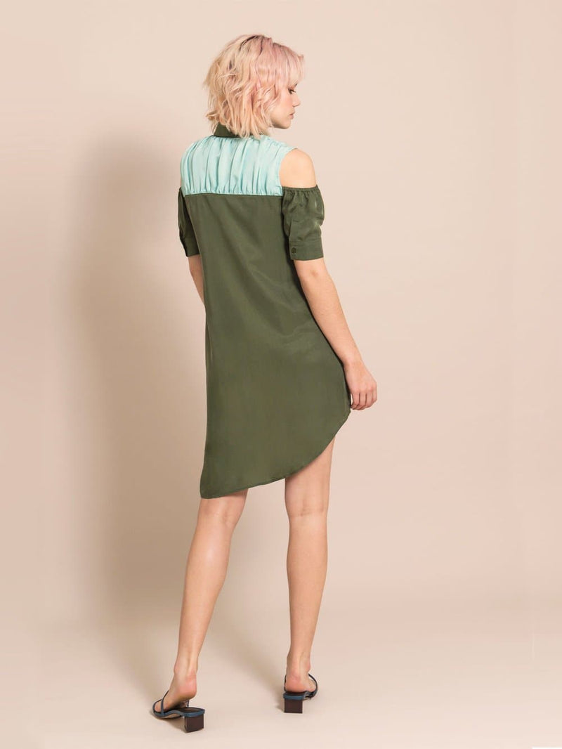 Backshot of a wodel wearing an above-the-knee, assymmetric military green dress made from cupro 