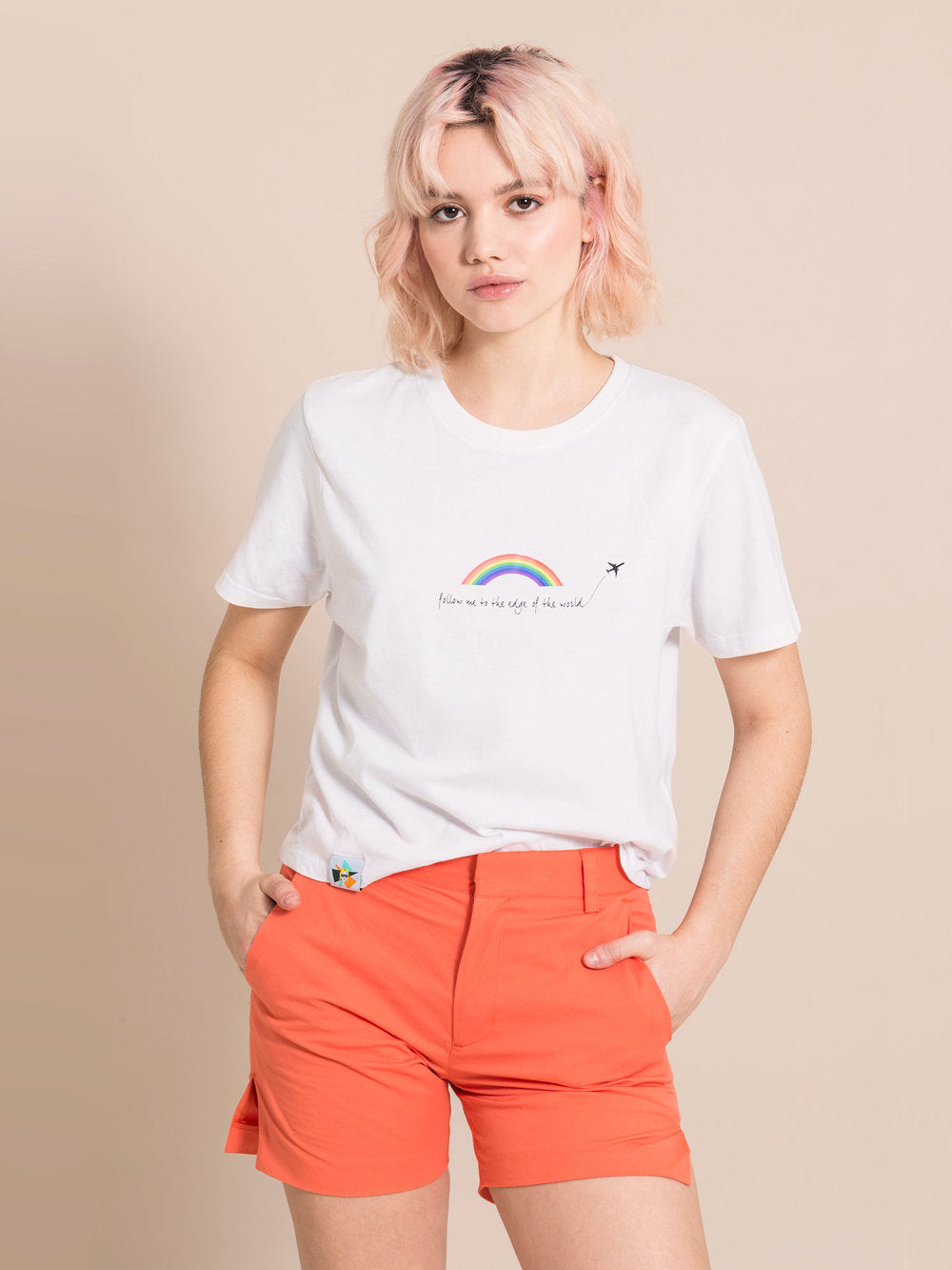 Frontshot of a woman wearing a white tee with print and orange sustainable shorts with crease