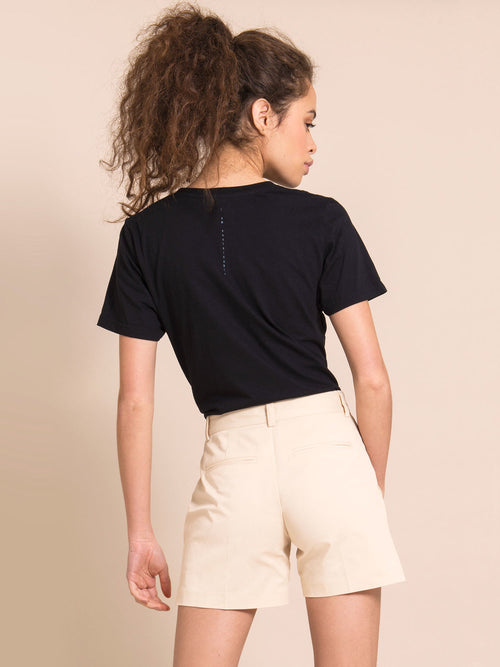 Backshot of a woman wearing black tee and beige shorts