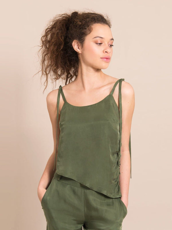 Frontshot of a girl wearing a sustainable  military green assymetric top with adjustable shoulder straps