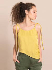 Frontshot of a woman wearing a sustainable  yellow assymetric top with adjustable thin shoulder straps