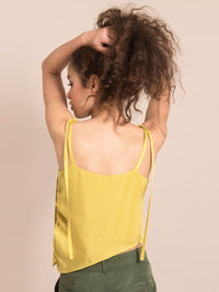 Backshot of a woman wearing a yellow top with thin shoulder straps