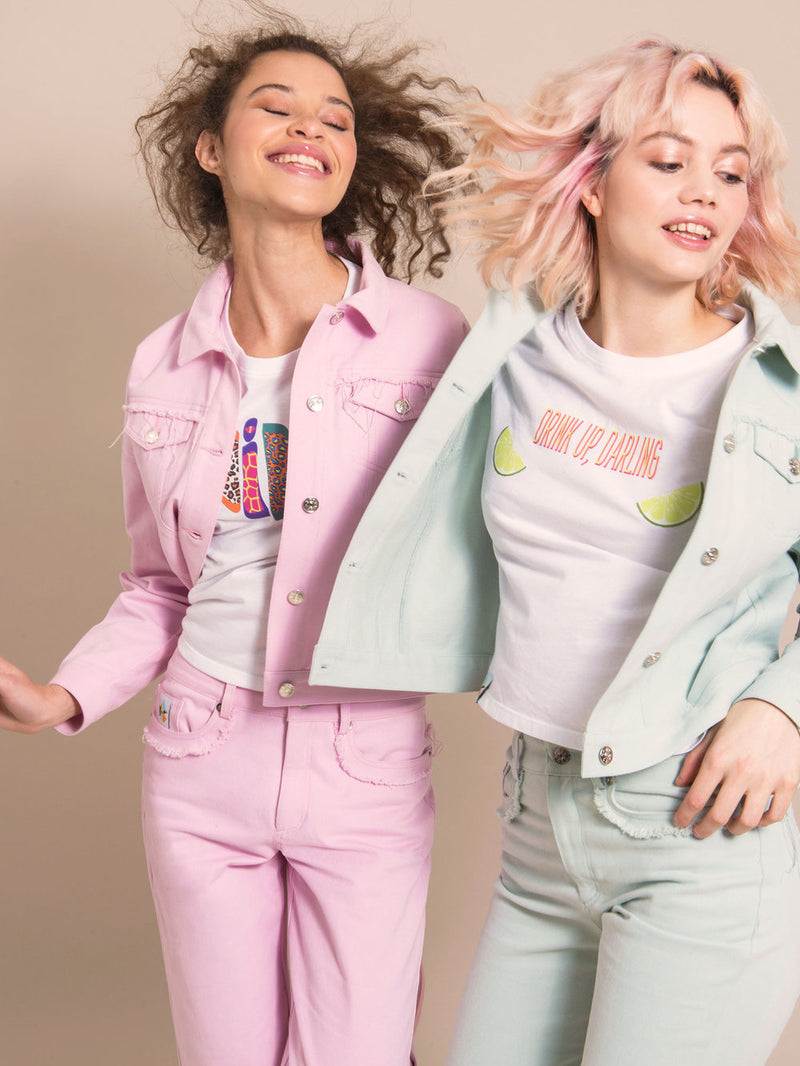 Two women wearing denim sets - one in light blue and one in light pink, with white tees underneath