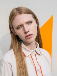 Close-up shot of a woman wearing a beige shirt with orange piping