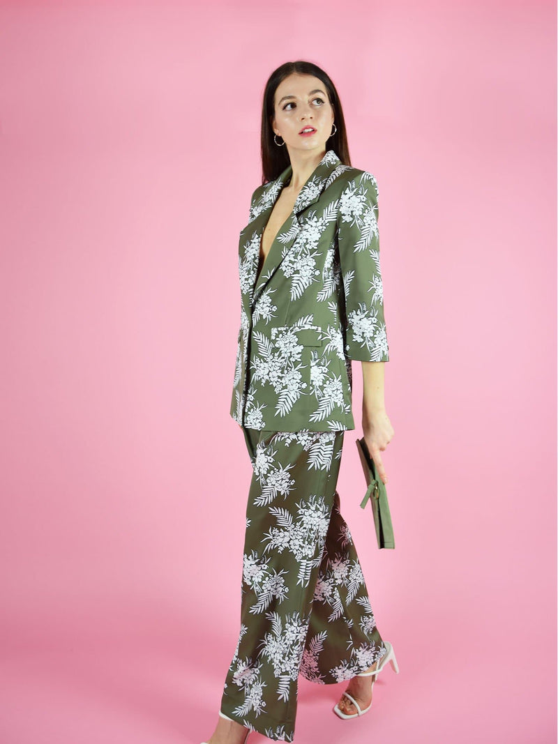 Sideshot of the sustainable trouser suit by blonde gone rogue. The pant suit consists of green with white print longline blazer and wide leg trousers.