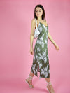 Motion shot of blonde gone rogue's midi slip dress in green paired with white high-heel sandals. 