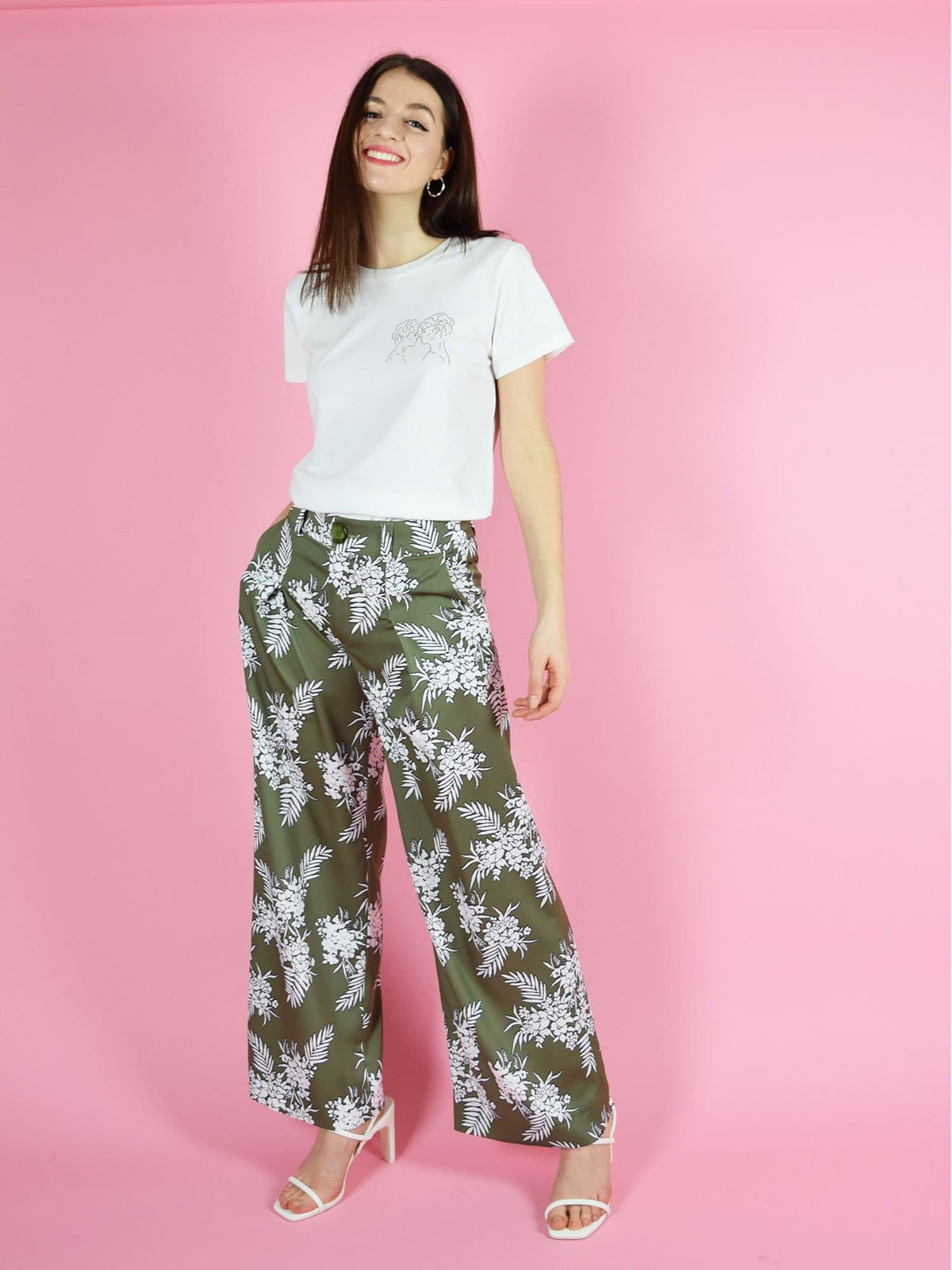 Frontshot of blonde gone rogue's lover's eyes organic cotton tee in white and the girlboss high wasited trousers in green with white floral print.