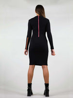 Back of the wicked zip dress in size XS has body con fit and comes in black. It has under knee length, long sleeves and two zippers. A pink zipper going from the neck to waist and a orange zipper on the left arm that unzips. 