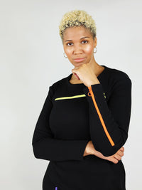Black wicked zipper dress has on orange zipper on the left arm and a bright yellow zipper under the collar bone area that can unzip. Long sleeves and round neck.